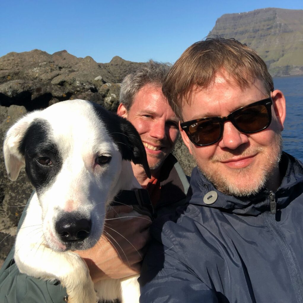 Man taking a selfie with the Akraberg lodge border collie dog on the cliffs